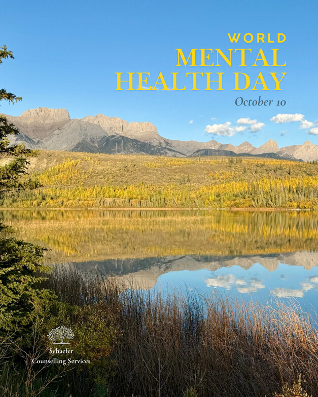Mountain lake surrounded by golden larch trees, with mountains and their reflections visible in the calm water on a clear autumn day.